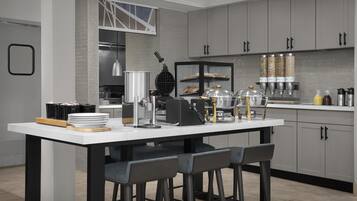 A modern kitchen with a central island, bar stools, and a bread display.