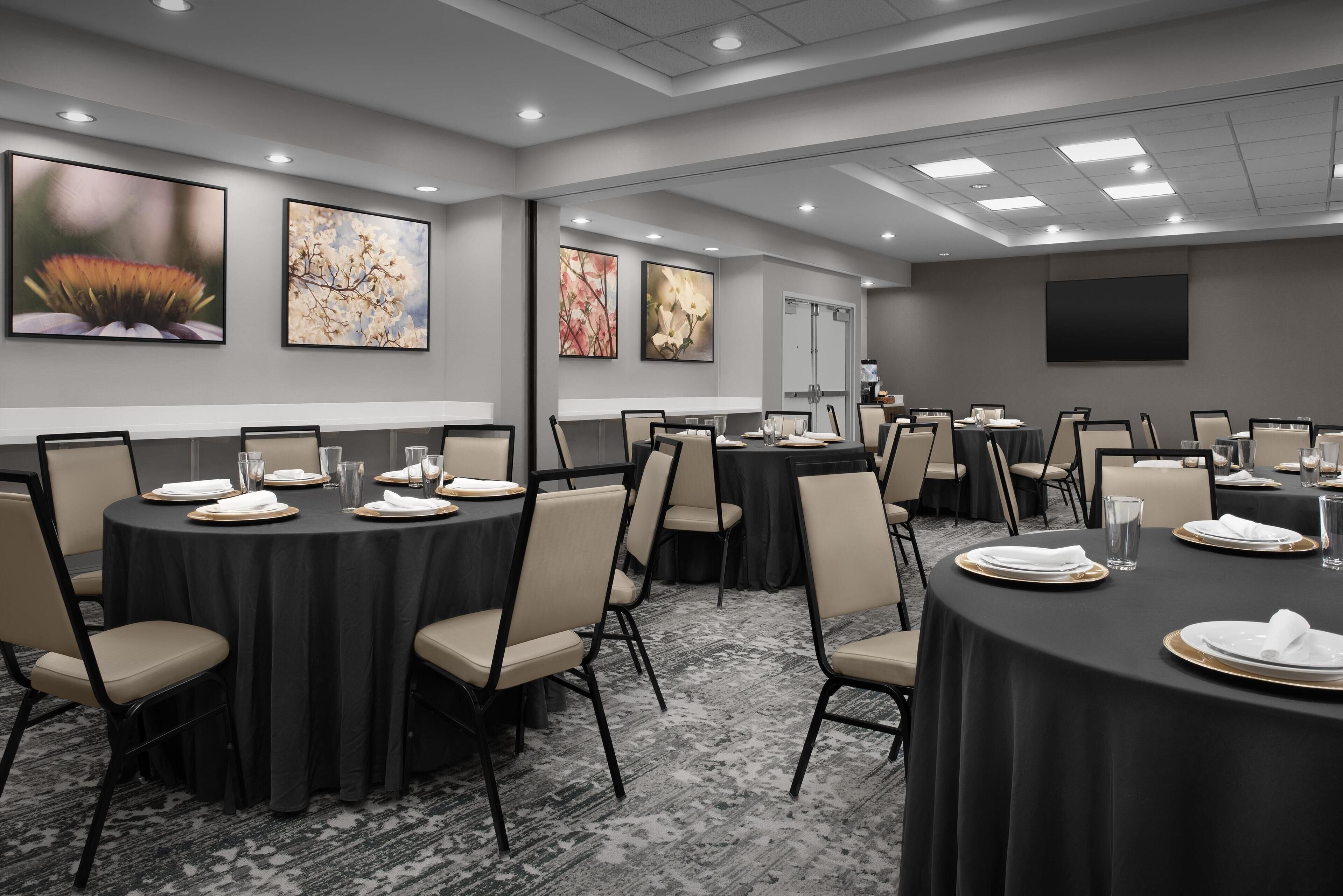 A conference room with round tables, chairs, and artwork on the walls.