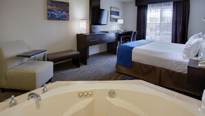Een hotelkamer met een groot bad, een bureau, een stoel, een bed en een televisie.