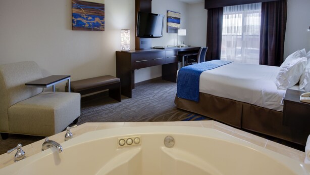 Une chambre d’hôtel équipée d’une grande baignoire, d’un bureau, d’une chaise, d’un lit et d’un téléviseur.
