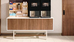 Een moderne keuken met een houten aanrecht, koffieapparaten en opbergboxen.