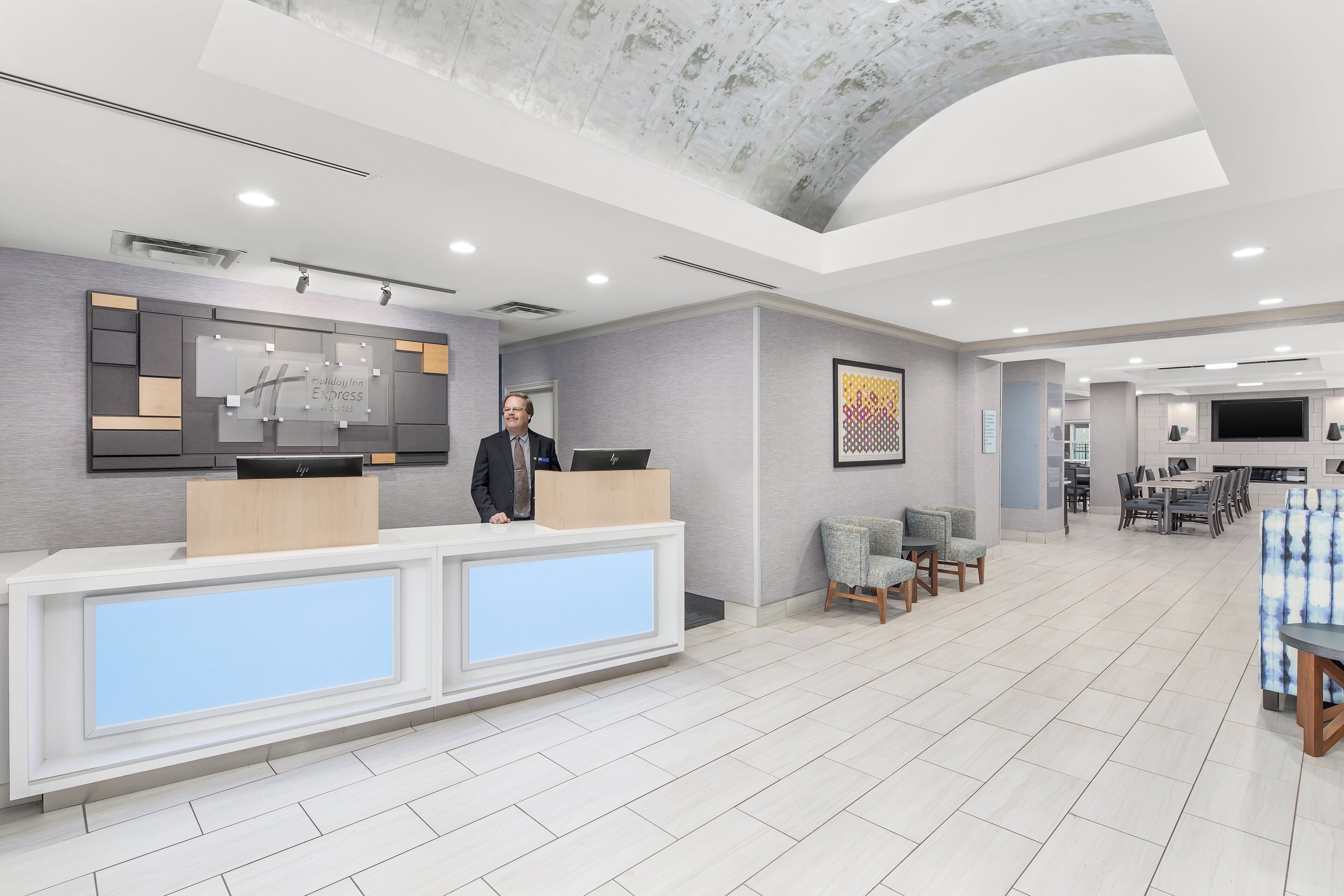 A hotel reception area with a modern design, including a reception desk, seating area, and a dining space.