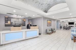 Een hotel receptie met een modern design, inclusief een receptiebalie, een zithoek en een eetruimte.