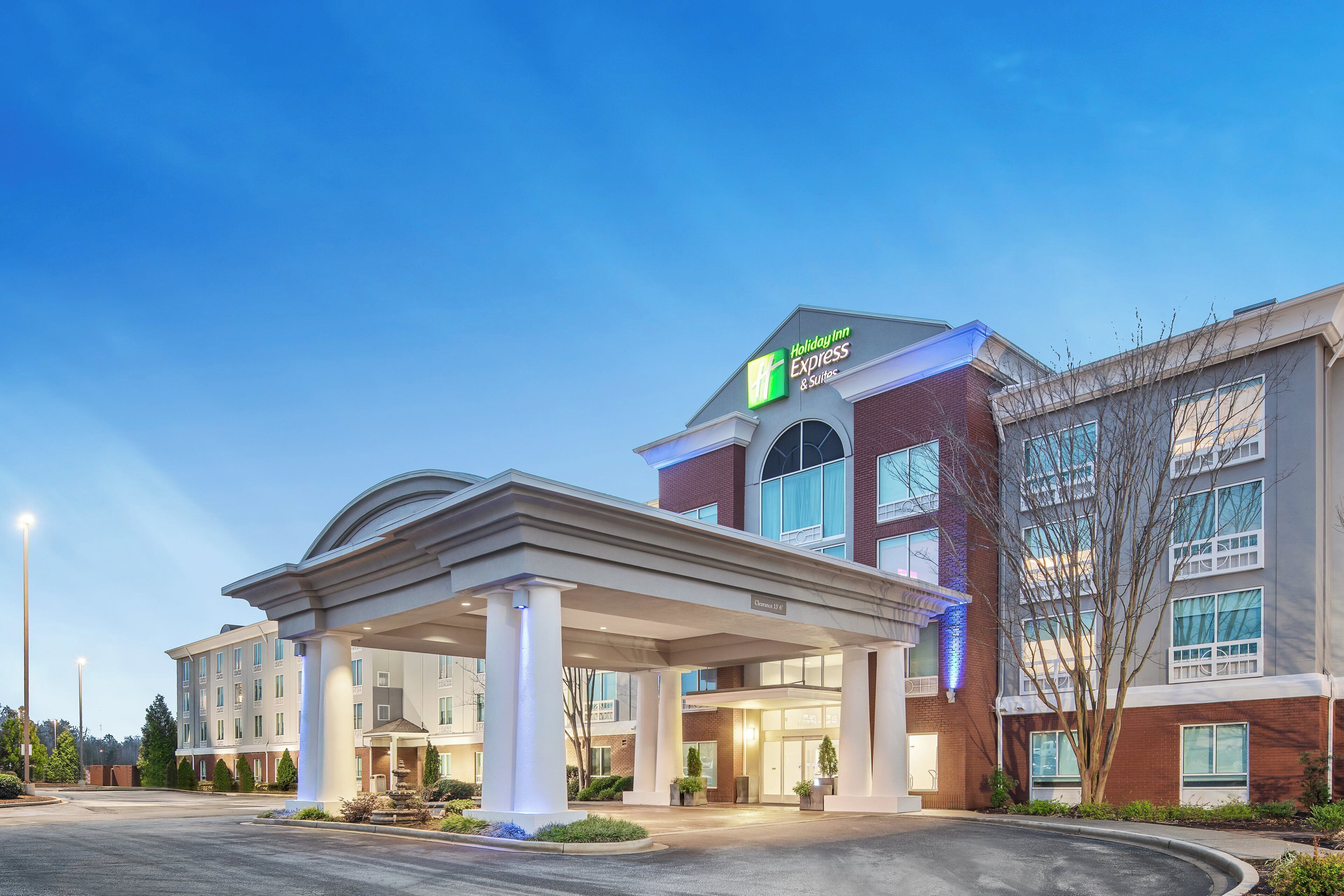 A Holiday Inn Express & Suites with a covered entrance and a clear sky.