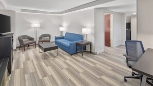 A modern hotel room with a sofa, two armchairs, a coffee table, a desk, and a TV. - Holiday Inn Express & Suites Greenville-I-85 & Woodruff Rd by IHG (Greenville)