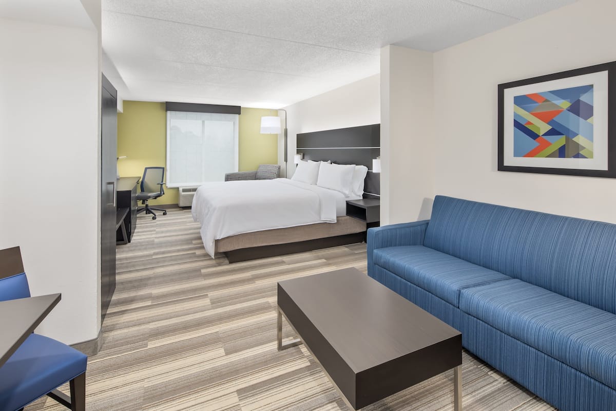 Une chambre d’hôtel moderne avec un lit, un canapé bleu, une table basse et un bureau avec une chaise.