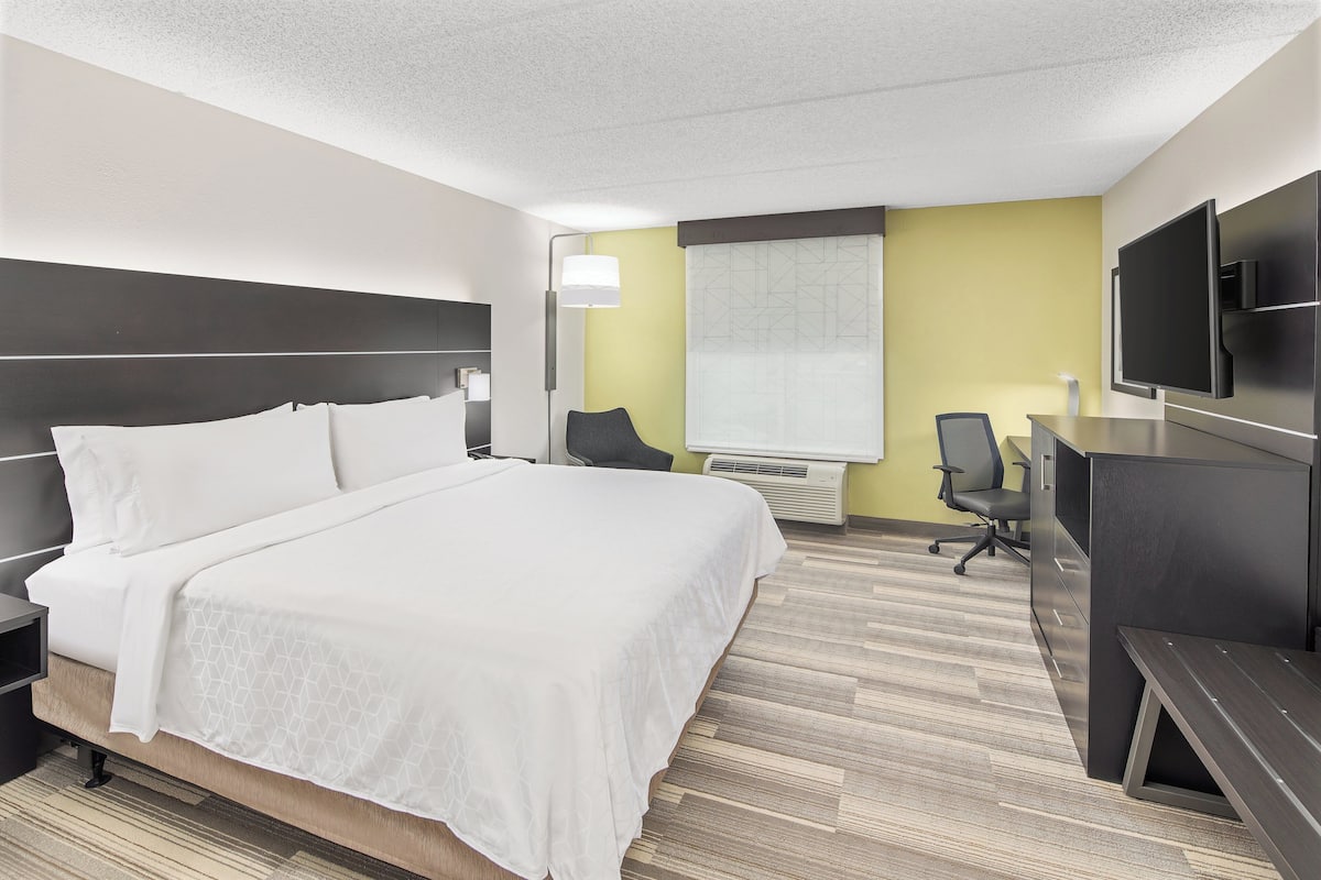 Une chambre d’hôtel avec un grand lit, un bureau, une chaise et un téléviseur à écran plat.