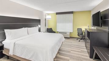 Une chambre d’hôtel avec un grand lit, un bureau, une chaise et un téléviseur à écran plat.