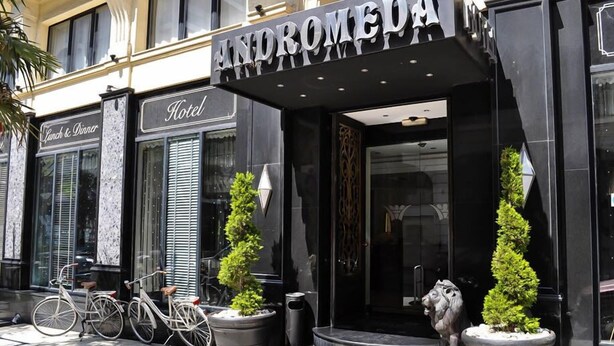 The exterior of the Andromeda Hotel with a black facade, a signboard, and two potted plants. - Andromeda Hotel Thessaloniki (Thessaloniki)