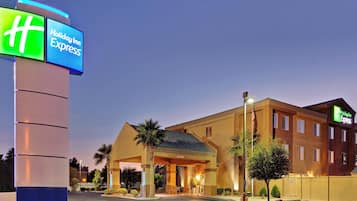 A Holiday Inn Express hotel with a prominent illuminated sign, a covered entrance, and a parking lot.