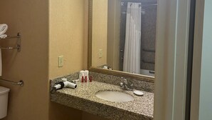 A bathroom with a granite countertop sink, a large mirror, and a towel rack. - Holiday Inn Express Las Vegas-Nellis by IHG (Las Vegas)