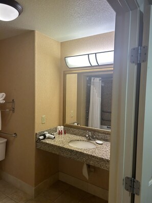 A bathroom with a granite countertop sink, a large mirror, and a towel rack. - Holiday Inn Express Las Vegas-Nellis by IHG (Las Vegas)
