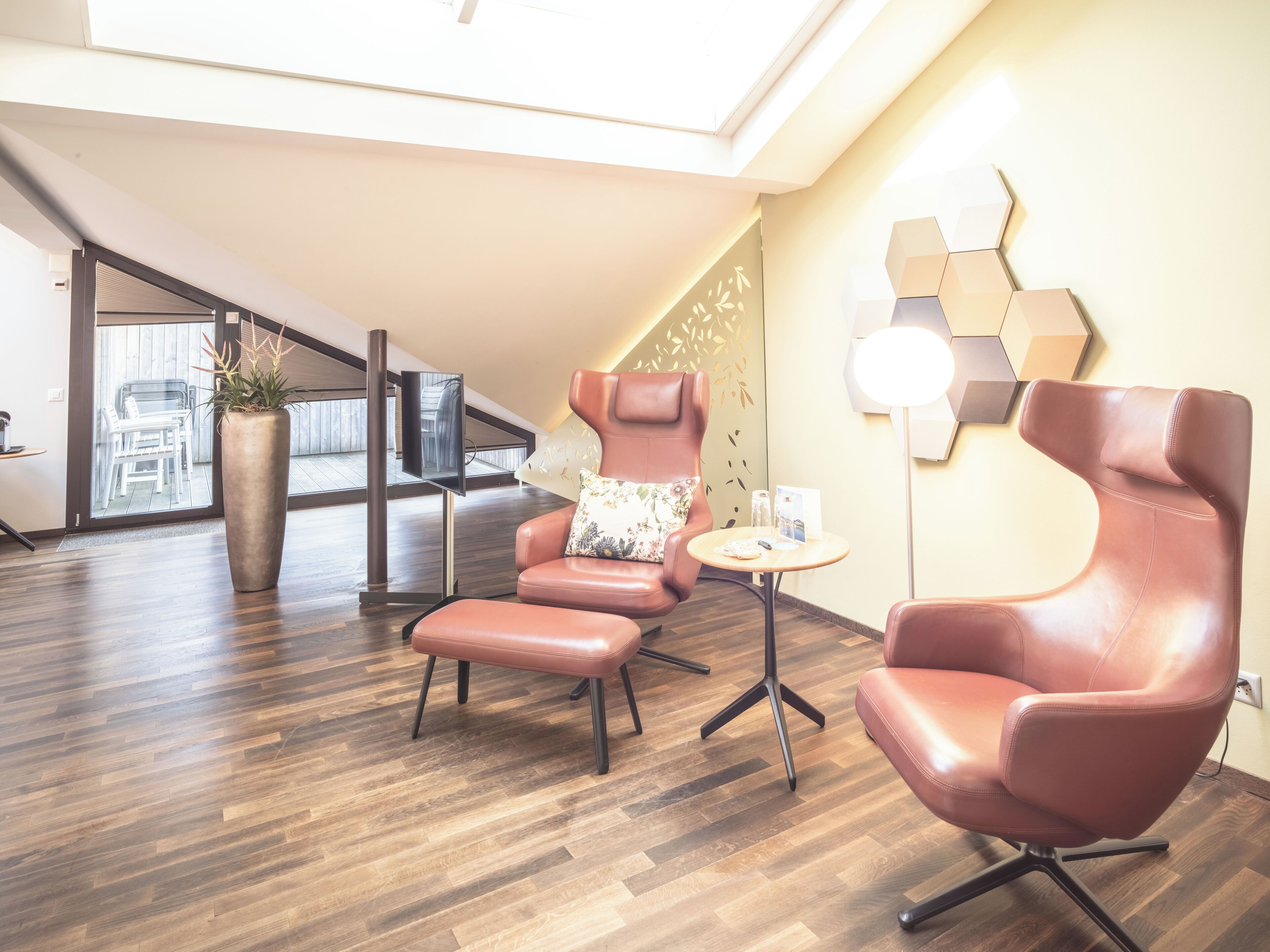A modern lounge area with leather chairs, a small table, and a TV.