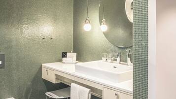 Une salle de bain moderne avec un grand miroir, deux lavabos, des toilettes et un petit tabouret.