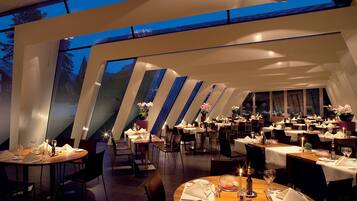 Un restaurante moderno con varias mesas de comedor, cada una decorada con velas y flores.