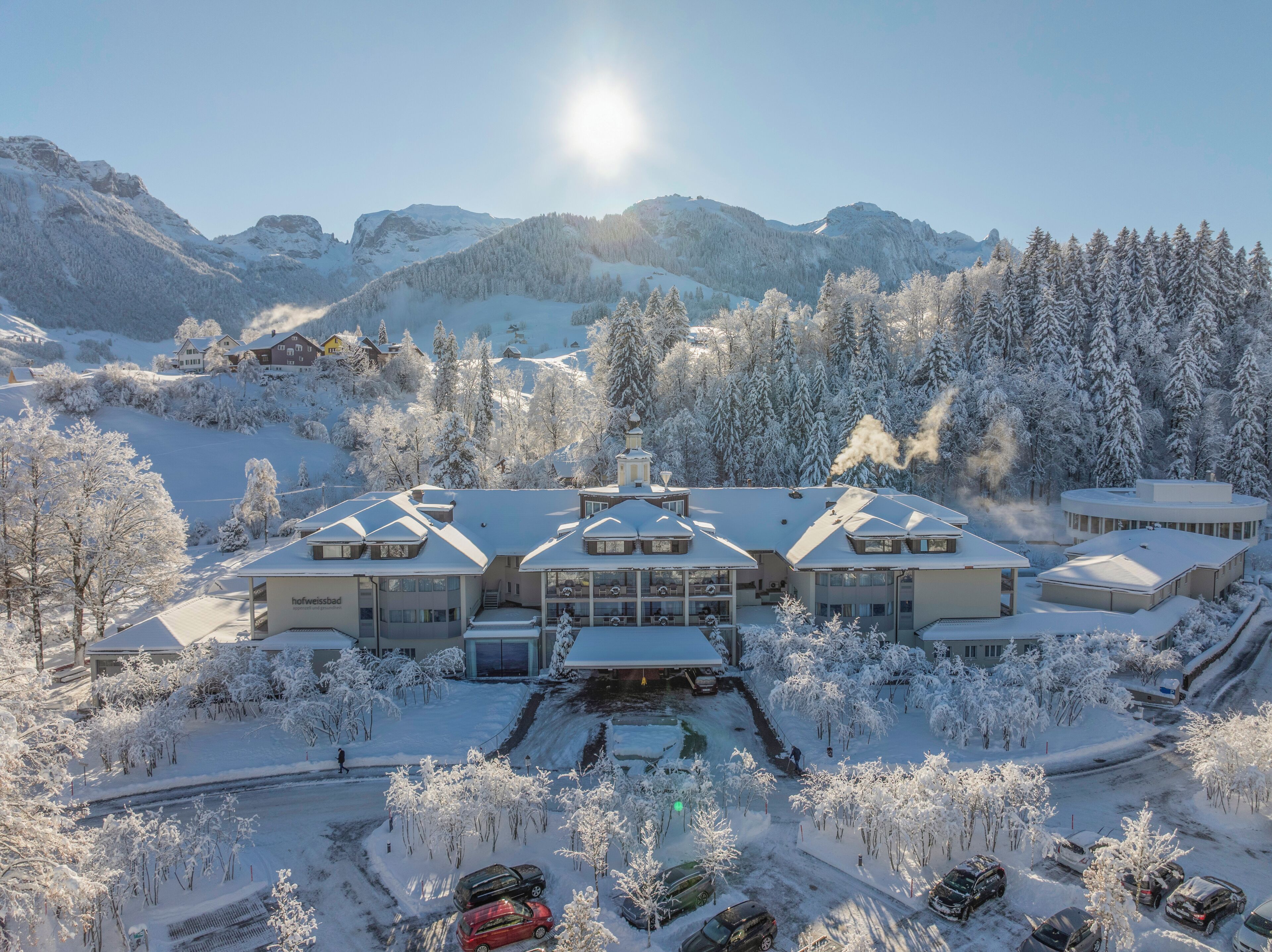 A modern hotel with multiple buildings, a ski slope, and snow-covered trees.