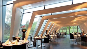 Un comedor moderno con mesas dispuestas para el servicio, ventanas amplias y vistas al exterior.
