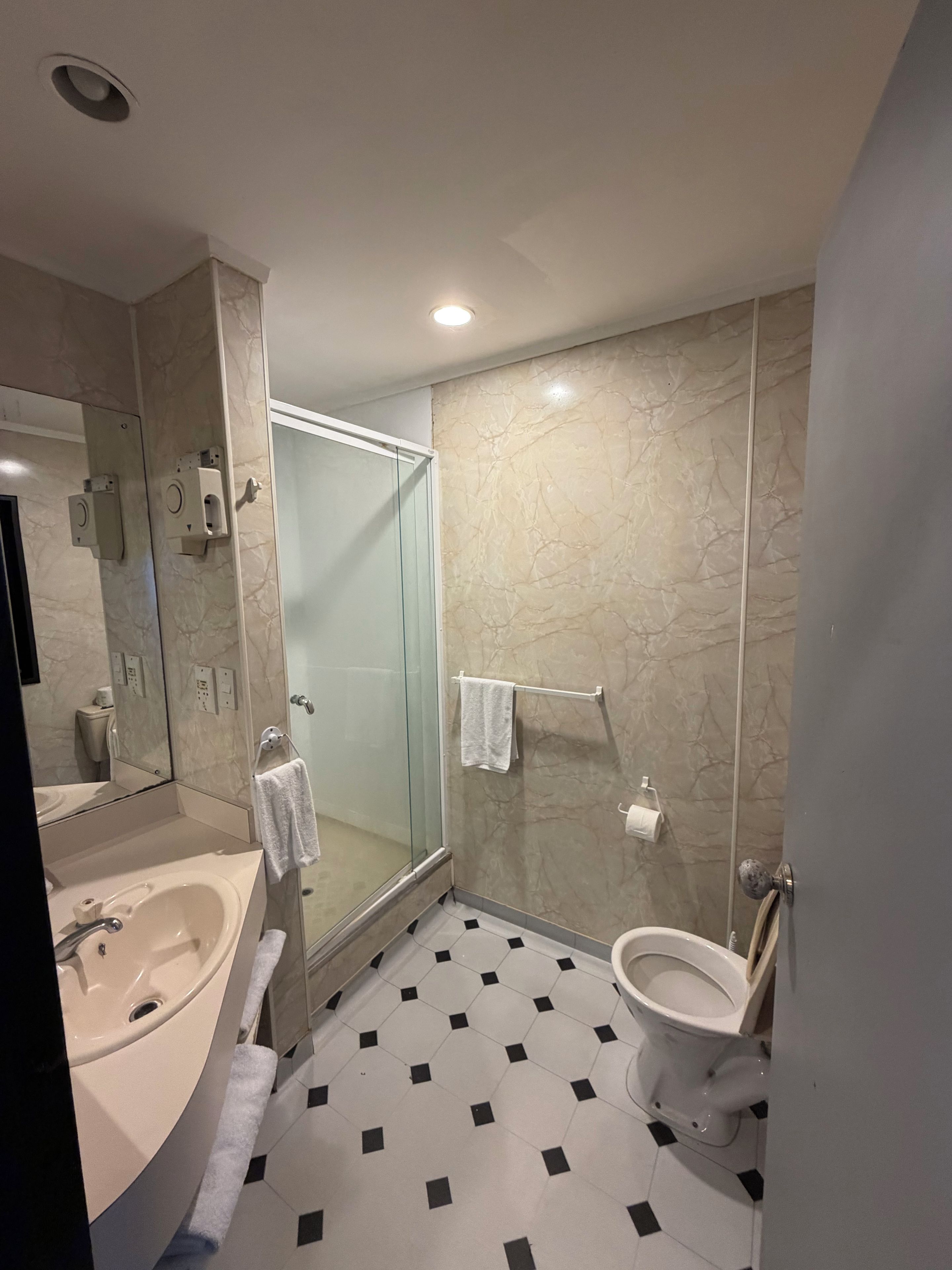 A modern bathroom with a glass-enclosed shower, a white sink, and a toilet.