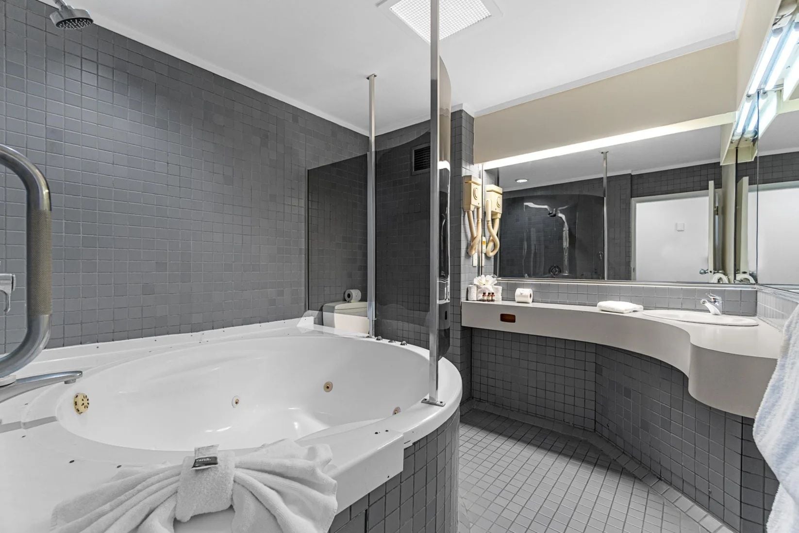 A modern bathroom with a freestanding bathtub, a large mirror, and a vanity with a sink.