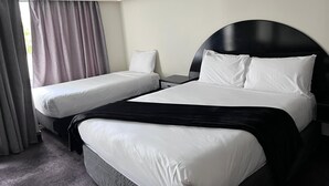 Et hotelværelse med to enkeltsenge og en større seng.
