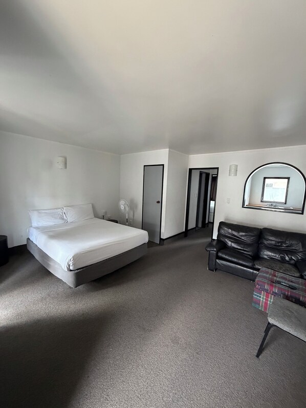 A hotel room with a bed, a sofa, a small table, and a mirror on the wall.
