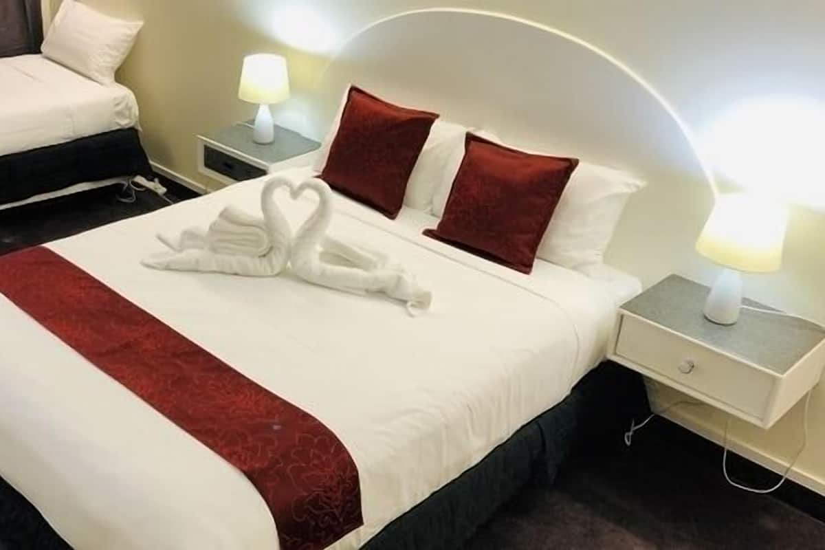 A hotel room with a large bed, a smaller bed, and a nightstand with a lamp.