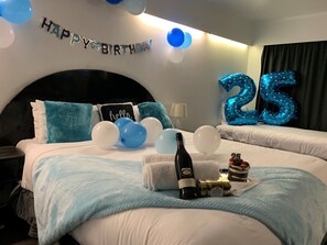 Enjoy a birthday celebration in style with a large bed, 'Happy Birthday' sign, and festive decorations.