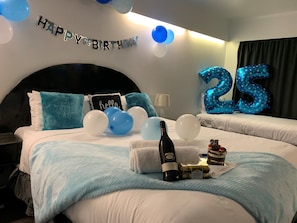 Enjoy a birthday celebration in style with a large bed, 'Happy Birthday' sign, and festive decorations.