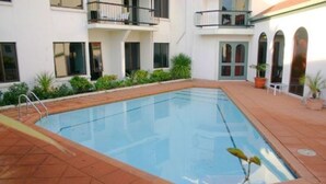 Et rektangulært pool med en stige på den ene side, omgivet af en fliseterrasse.