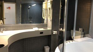 Et moderne badeværelse med et stort spejl, et badekar, en bruseniche og et toilet.