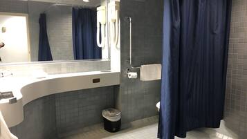 A modern bathroom with a white sink, a mirror, a towel rack, a shower curtain, and a toilet.