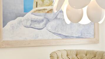 Ein Zimmer mit einem gerahmten Gemälde einer verschneiten Landschaft, einem geschnitzten Sofa und einer modernen Chandelier.