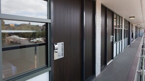A corridor with a modern design, featuring a combination of glass and dark wooden panels.