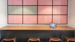 A modern kitchen with a wooden countertop, a laptop, and a large window with pink and green panels.