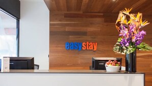 A reception desk with a wooden wall background and a sign that reads "easy stay."