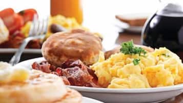 A breakfast plate with scrambled eggs, bacon, and toast.