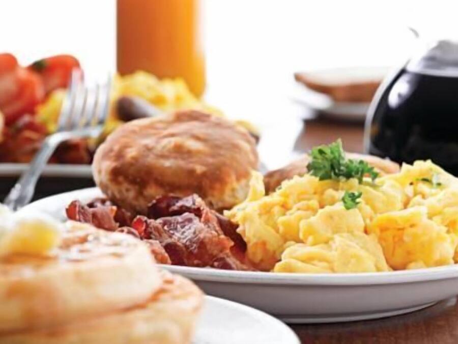 A breakfast plate with scrambled eggs, bacon, and toast.