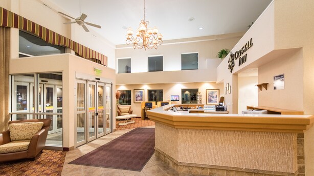 A hotel lobby with a reception desk, seating area, and glass doors leading to rooms. - Crystal Inn Hotel & Suites Great Falls (Great Falls)