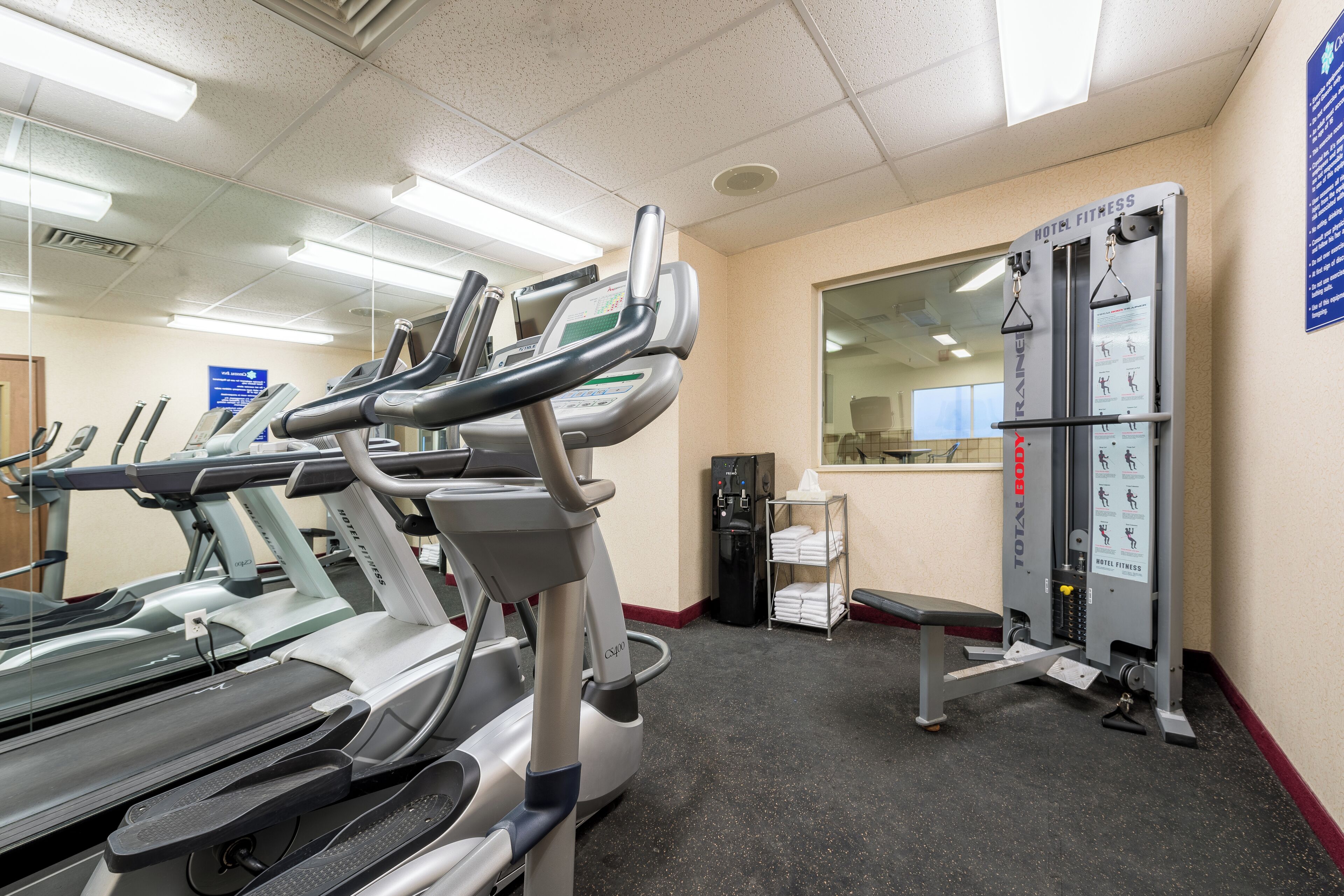 A hotel fitness center with treadmills, a weight machine, and a water cooler.