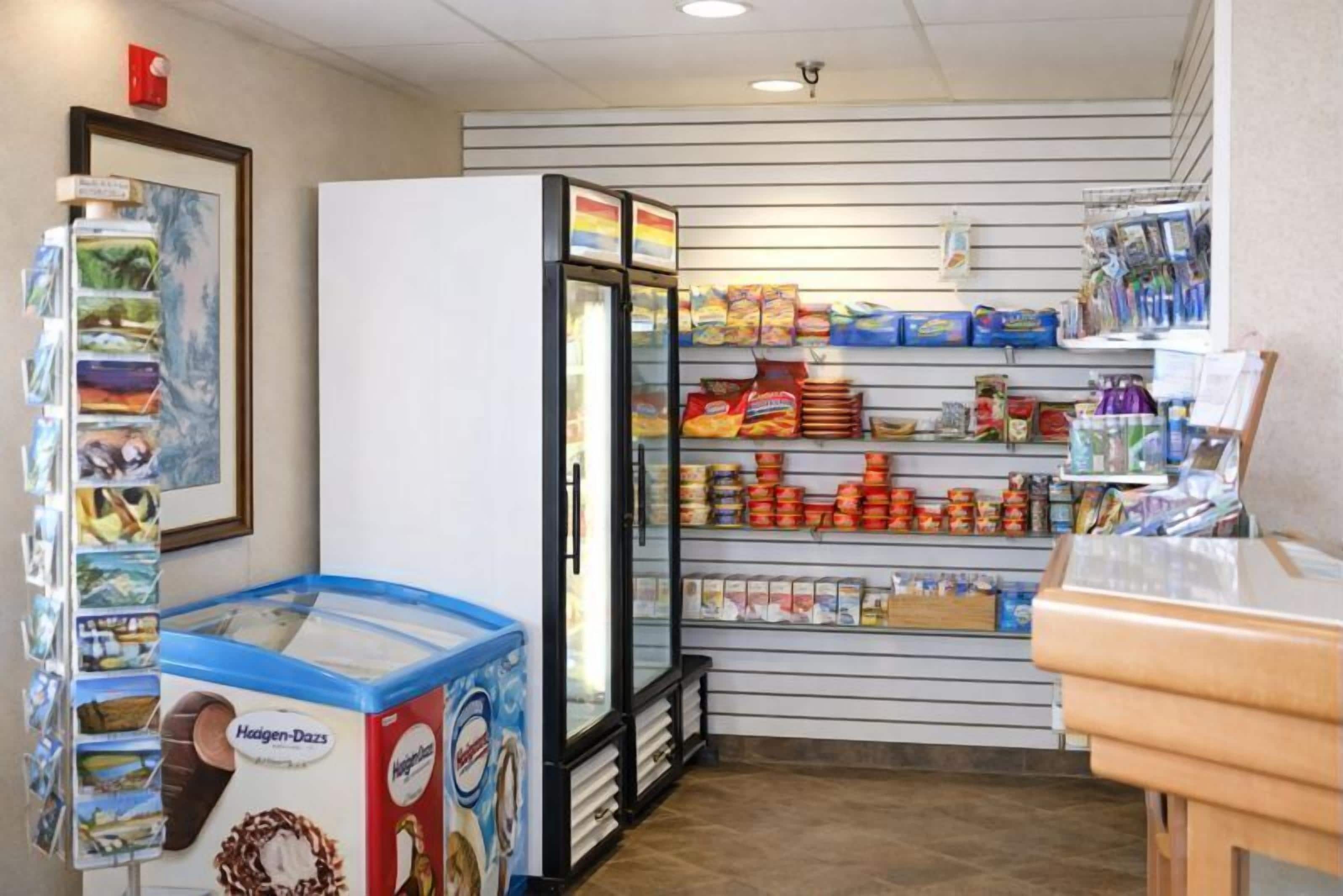 En lille dørafhentning med køledisk, hylder med snacks og et udvalg af is