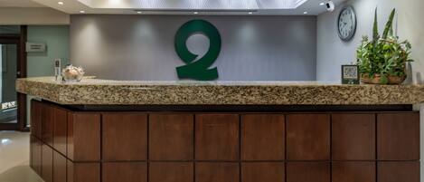 A reception desk with a large '2' sign, a clock, and a potted plant.