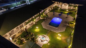 An aerial view of a hotel courtyard at night with a swimming pool, outdoor seating, and well-lit pathways. - Quinta Dorada Hotel and Suites (Saltillo)