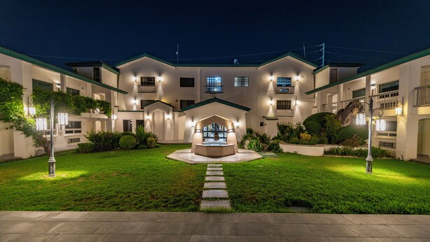 A hotel with a central courtyard, multiple balconies, and a well-lit entrance. - Quinta Dorada Hotel and Suites (Saltillo)