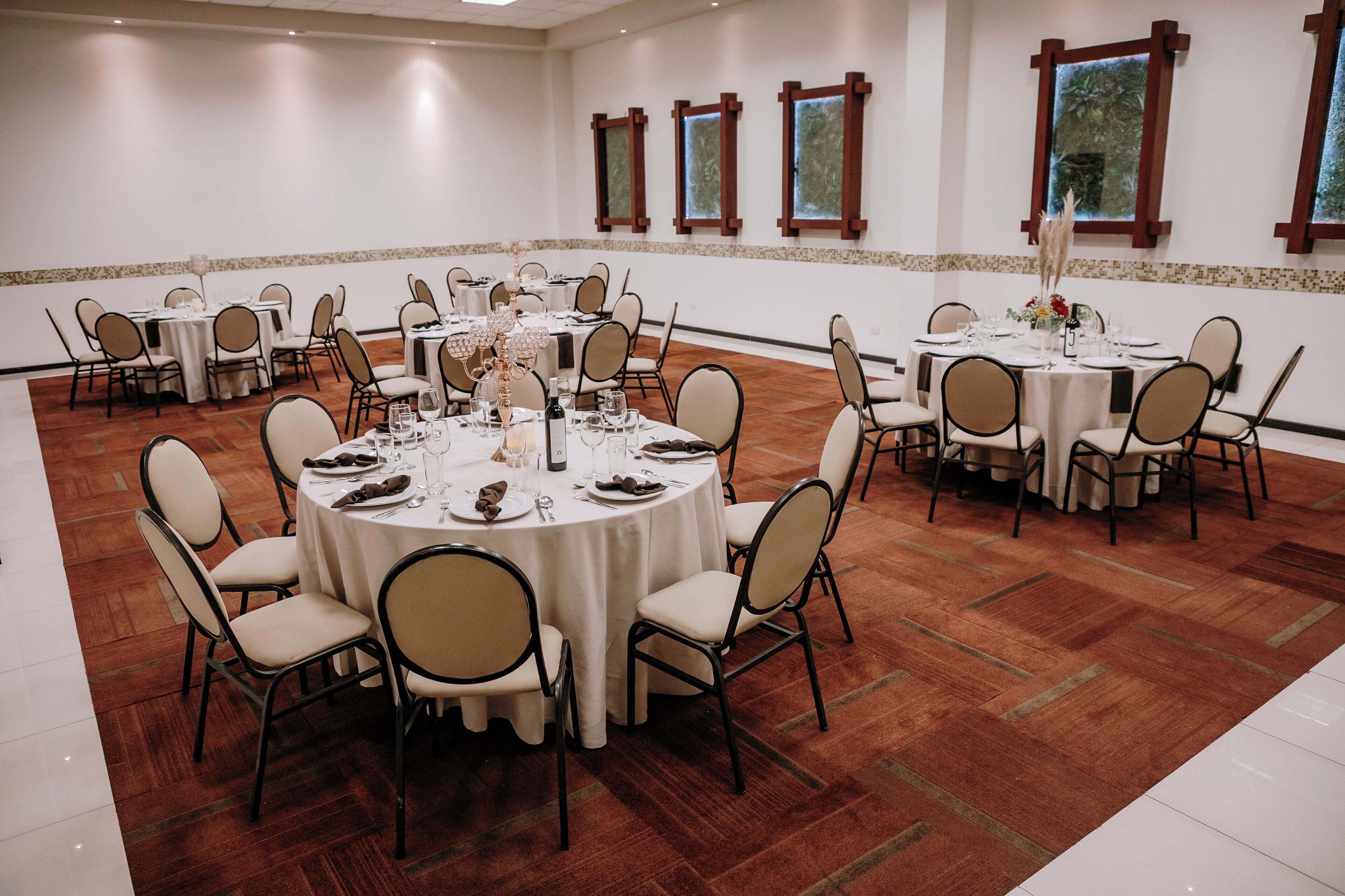 A conference room with round tables, chairs, and a polished wooden floor.