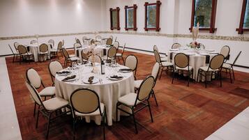 A conference room with round tables, chairs, and a polished wooden floor.
