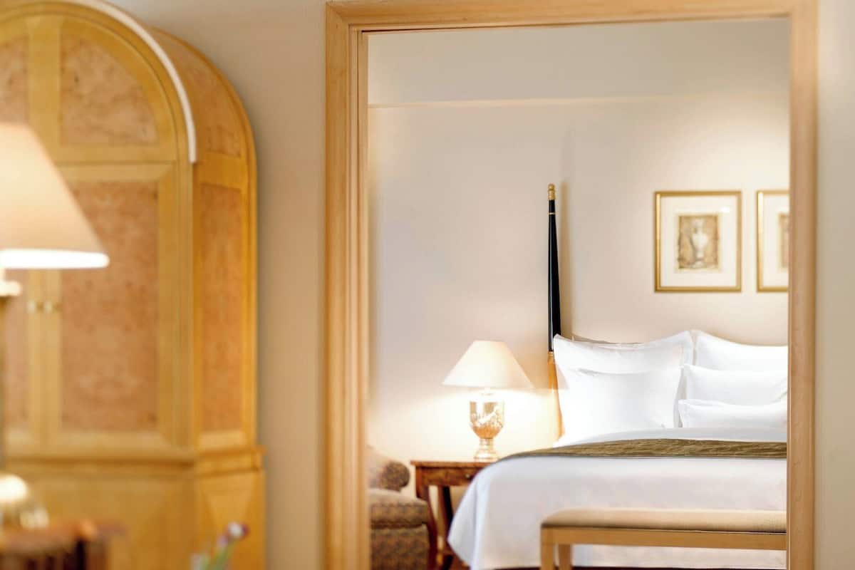 Ein Hotelzimmer mit einem Bett, einem Nachttisch, einer Lampe und einem Holzsessel.