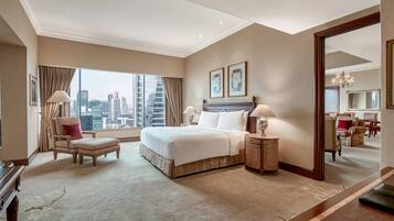 A spacious hotel room with a large bed, a sitting area, a view of the city skyline, and a large mirror.