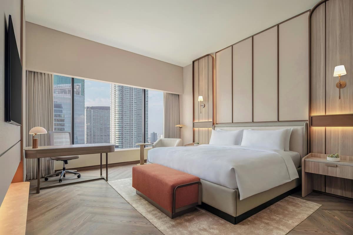 Ein modernes Hotelzimmer mit einem großen Bett, einem Schreibtisch und Blick auf die Stadtlandschaft.