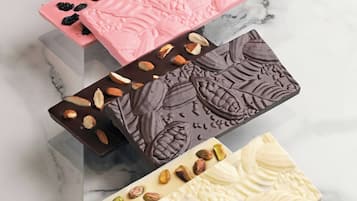 Four rectangular chocolate bars with different toppings on a marble surface.