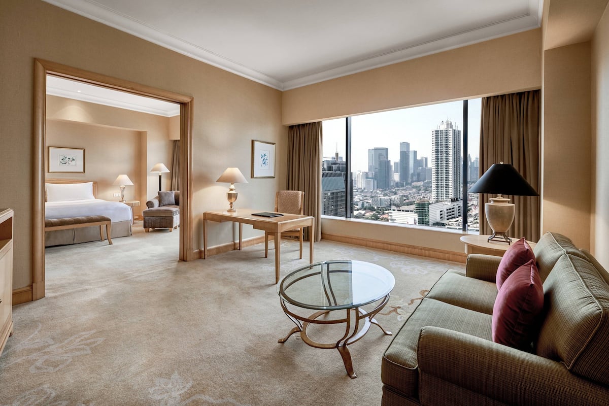Ein Hotelzimmer mit Bett, Glastisch, Sofa und Blick auf die Skyline der Stadt.